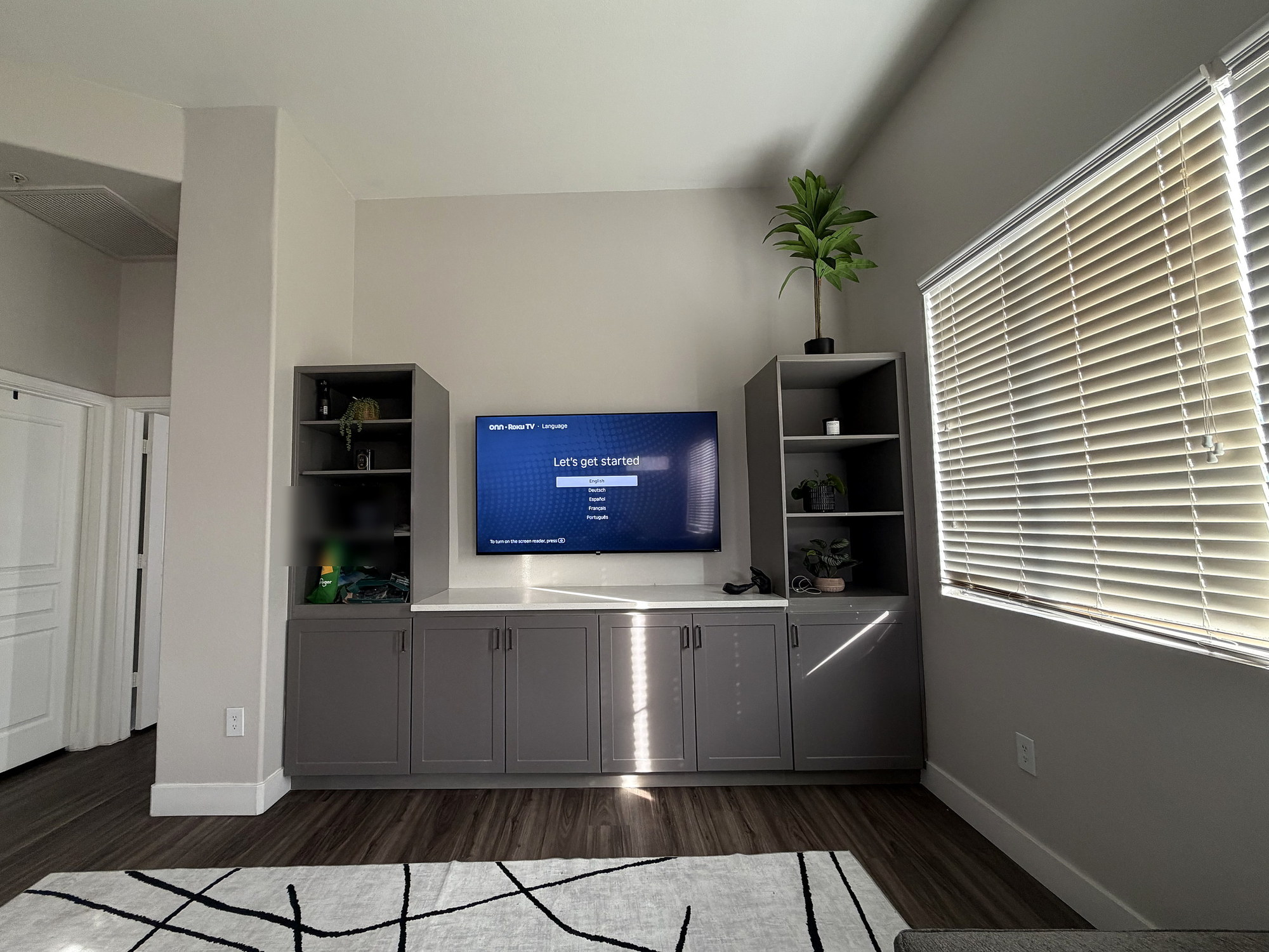 TV mounted centered between gray built-in cabinets and shelving