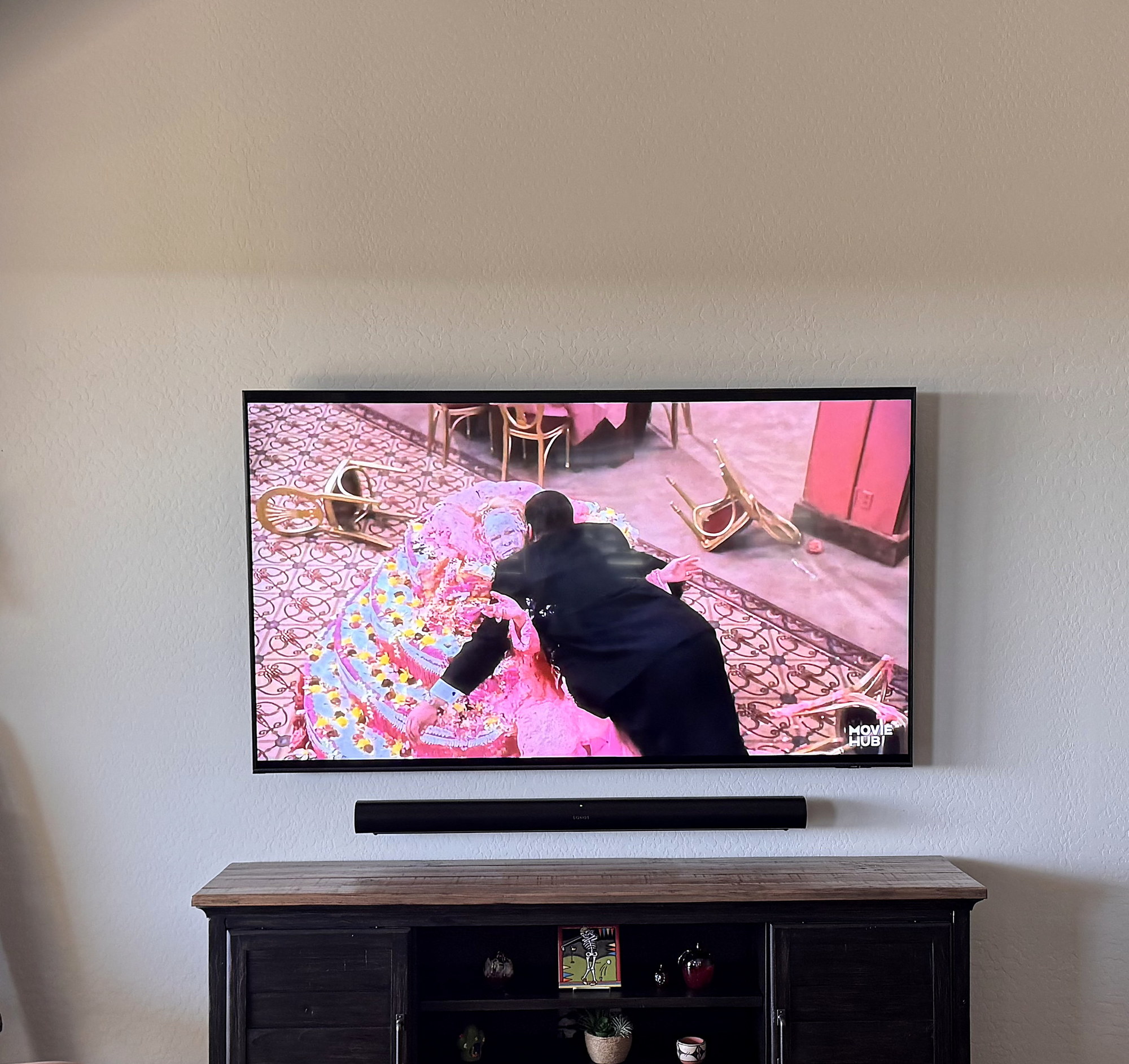 TV with a wall-mounted soundbar above a dark farmhouse media console