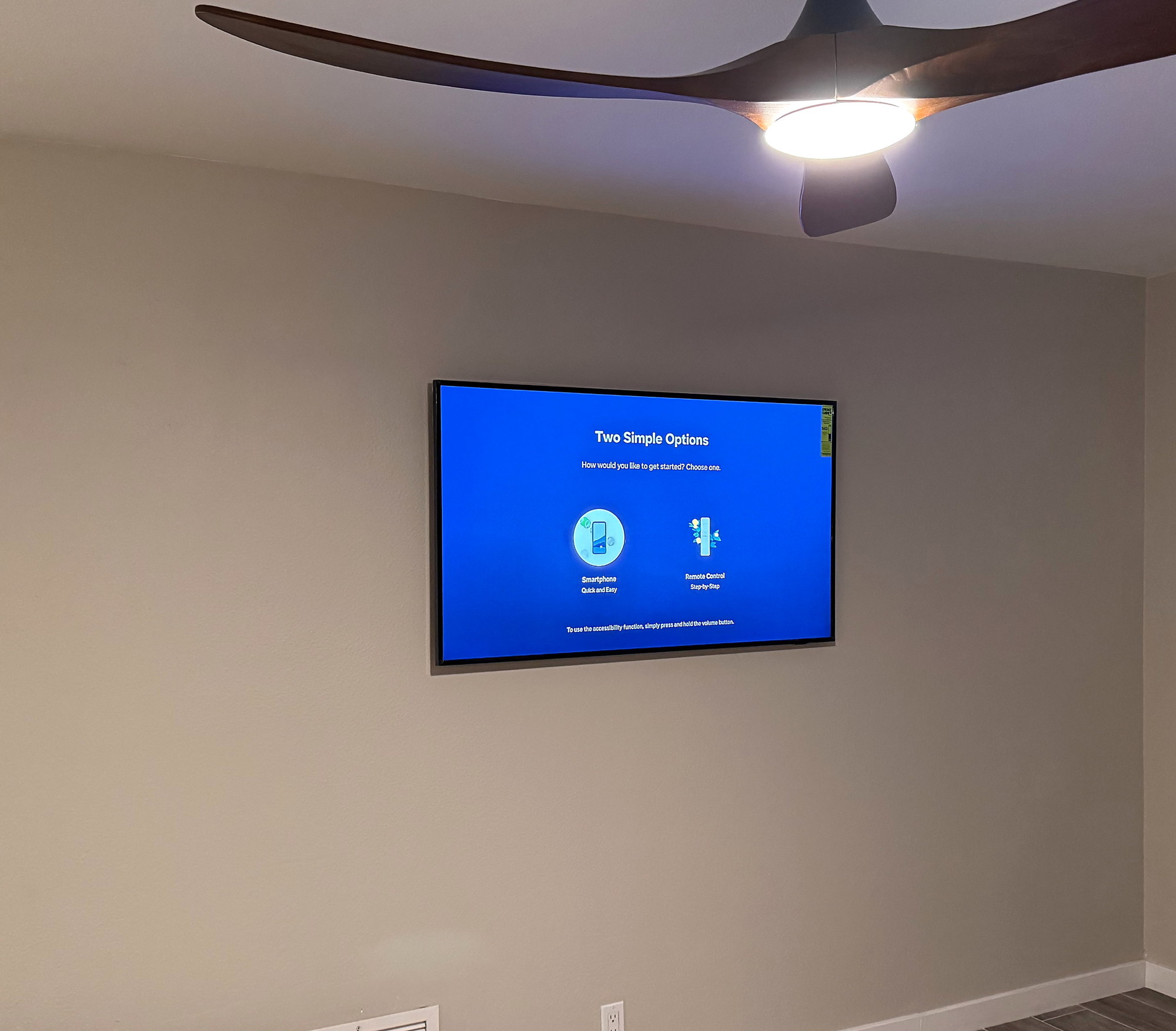 TV mounted on an open wall beneath a wood-blade ceiling fan