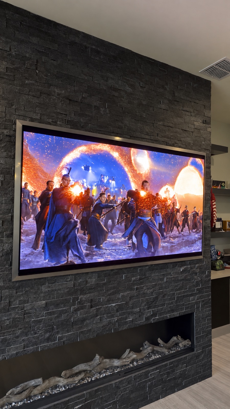 83-inch Samsung S95H OLED mounted flush on a stone fireplace wall